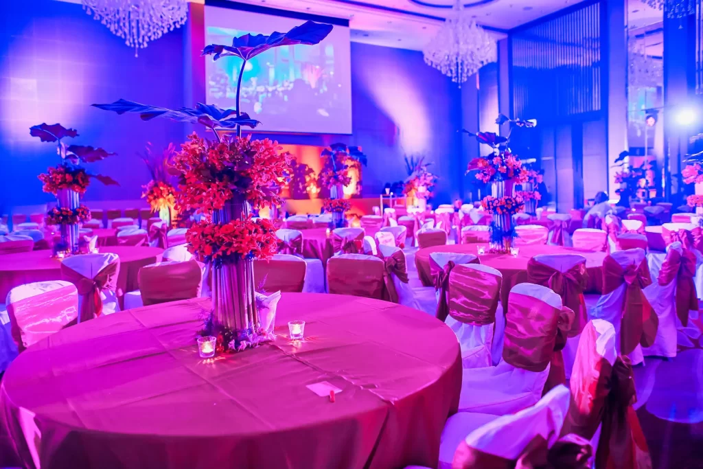 Event venue with vibrant lighting and decorated tables creating an elegant atmosphere.